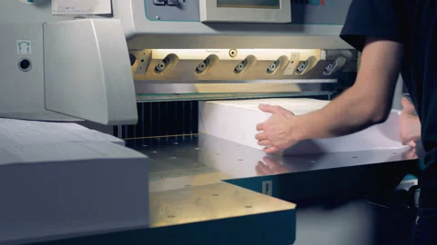Printing house worker operating cutting machine. Worker cutting a stack of paper Stock Footage 86414120