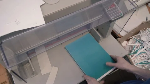 Printing house worker operating cutting machine. Worker cutting a stack of paper Stock Footage 105925422