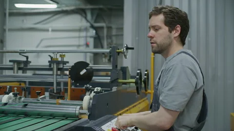 Printing Press Operator Adjusting Machinery in Industrial Print Shop Stock Footage 335484021