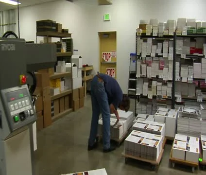 Printing press operator sorts through finished materials on pallets Video stock 21596902
