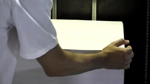 A printing press worker adding paper to a industrial printing machine 스톡 동영상 242803272