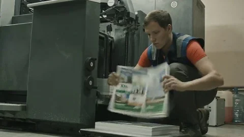 Printing process in machine of printing conveyor - worker inserts paper sheets Stock Footage 69091616
