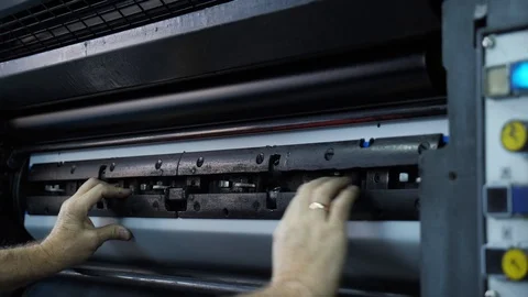 A printing worker inserts a form into the printing press with a tool. Stock Footage 98120934