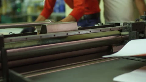 Prints being inserted into a roller press machine Stock Footage 295342793