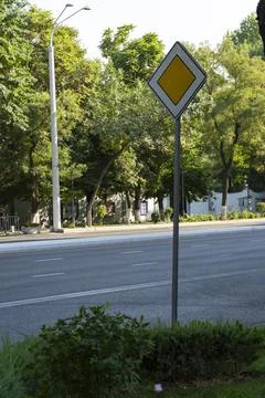 Priority Road Sign on Tree-Lined Street Stock Photos