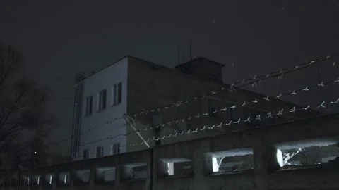 Prison barbed wire over concrete fence at cold dark winter night during snowfall Stock Footage 154104775