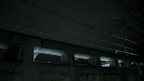Prison barbed wire over concrete fence at cold dark winter night during snowfall Stock Footage 154191766