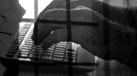 Prison bars are placed on the hands of a programmer typing a code on a comput Stock Photos