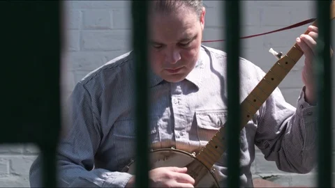 Prison Convict in real Jail Cell with Iron Bars - plays Banjo. Al Capone Stock Footage 86317619