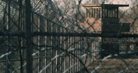 Prison, correctional facility exterior. Pan from Razor wire to Gaurd Tower. Stock Footage 143760220