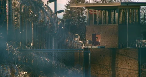 Prison, correctional facility. Guard tower surrounded by razor wire fencing Stock Footage 143760946