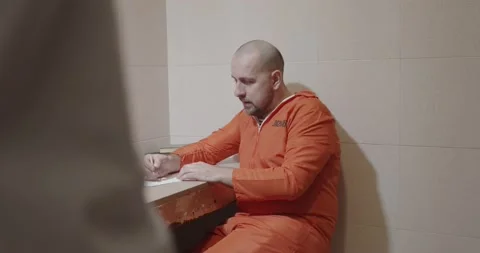Prison guard approaches a prisoner while writing a letter. Stock Footage 171089506