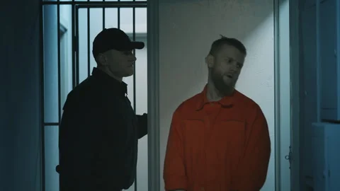 Prison guard escorting a handcuffed male inmate to the visitation room Stock Footage 340031821