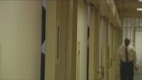 Prison guard walking along jail cells Stock Footage 101624316