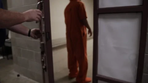 Prison guards escort a prisoner into his cell and shut prison door locking Vidéo 254401716