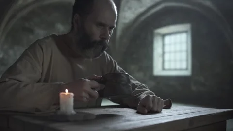 Prison inmate drinking from a rustic mug and looking down thoughtfully Stock Footage 339631197