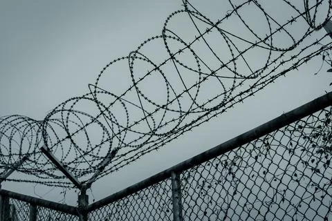 Prison security fence. Barbed wire security fence. Razor wire jail fence. Bar Stock-Fotos