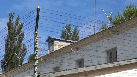 The prison is surrounded by a fence with barbed wire under high voltage Stock Footage 77877578