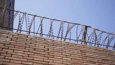 Prison yard. A brick wall with a security wire fence. Stock Footage 256297810