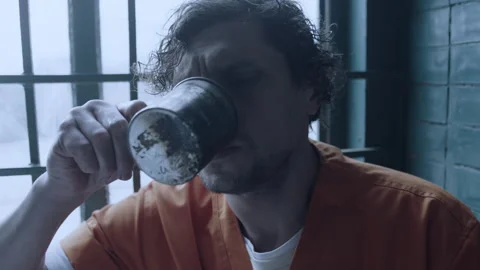 A prisoner drinking something out of a rusty cup Stock Footage 283089354