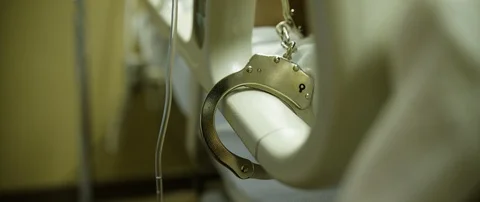 Prisoner with hand cuff lying on the hospital bed Stock Footage