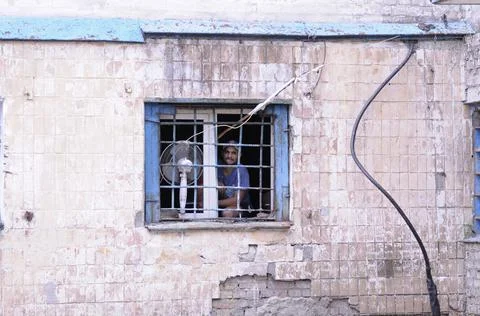 Prisoner looking out through prison bars on the window Stock Photos