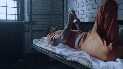 A prisoner reading a book in his cell Stock Footage 283089880