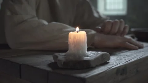 Prisoner scratching skin on arm next to a burning candle, tracking shot Video stock 340823775