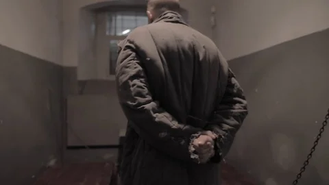 Prisoner in trashy clothes sitting in a cell 動画素材 126035202