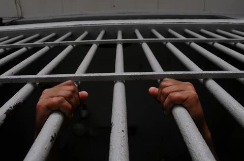 Prisoner&amp;#039;s hands behind bars Stock Photos