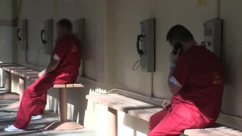 Prisoners speak on the phone and sleep on bunk beds from a local jail. Stock Footage