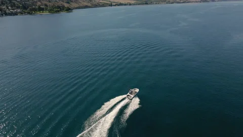 Pristine Blue Lake Water with Drone Following Motorboat Cruising in Desert En Stock Footage 140840517