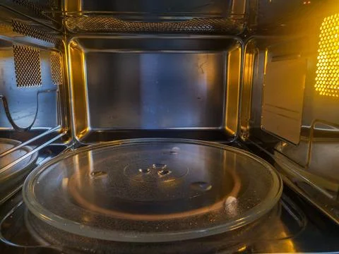 A pristine, empty microwave oven interior glows with warm golden light over i Stock Photos