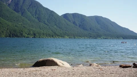 Pristine Lakeside Scenery with Distant Kayakers and Mountains Stock Footage 254982888