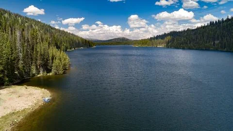 Pristine Mountain Lake Surrounded by Pine Forest Under Blue Sky Stock Photos