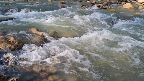 Pristine mountain river rushing over rocky terrain, generating cascading white Stock Footage 308084310