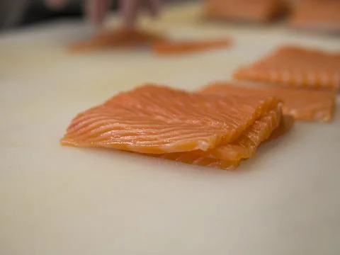 A pristine piece of salmon is carefully placed on a kitchen board, its deli.. Stock Photos