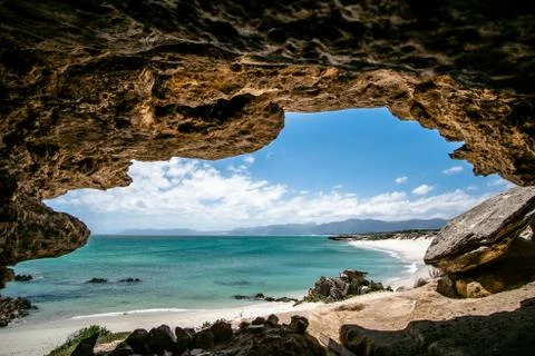 Pristine stretch of secluded beach, shot from within big cave Stock Photos