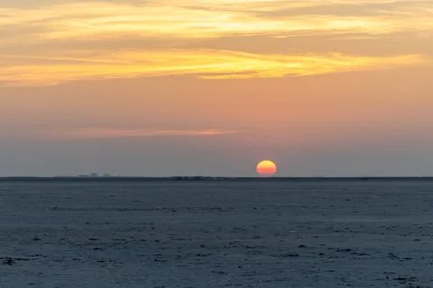 Pristine sunset over white salt flats desert with dramatic orange sky at dusk 写真素材