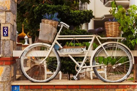 A pristine white bicycle featuring a basket and a sign that says beach Stock Photos