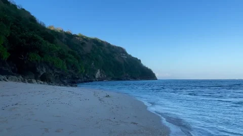 Pristine White Sand Beach and Green Coastal Cliff in Bali Stock Footage 337336420