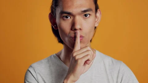 Private asian guy doing hush silent sign on camera Stock Footage 233541752