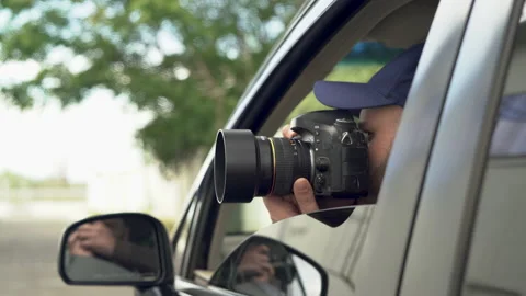 Private detective sitting inside car taking picture with professional slr camera Stock Footage 220762401