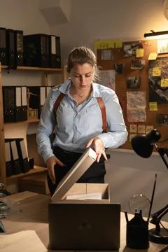 Private detective studying case files in evidence room. Female detective wo.. Stock Photos