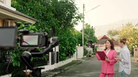 With a private house in the backdrop, a cameraman is using a crane-mounted Stock Footage 240650680