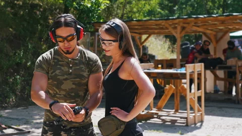 Private instructor at shooting range showing basic black gun to his female Video stock 215716386
