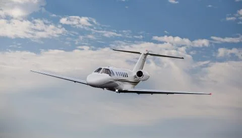 Private jet in the air with clouds in the background Stock Photos