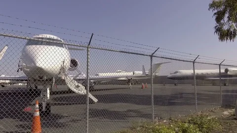 Private Jets at Airport View through Fence Line Pan Shot 01 Video stock 93522650