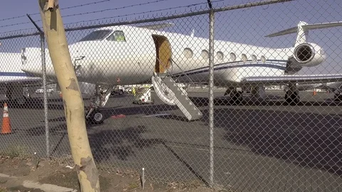 Private Jets at Airport View through Fence Line Pan Shot 02 Stock Footage 93522802