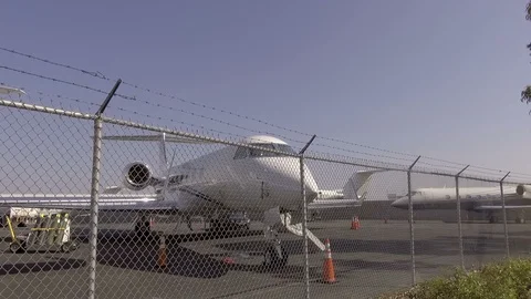 Private Jets at Airport View through Fence Line Pan Shot Stock Footage 93523091
